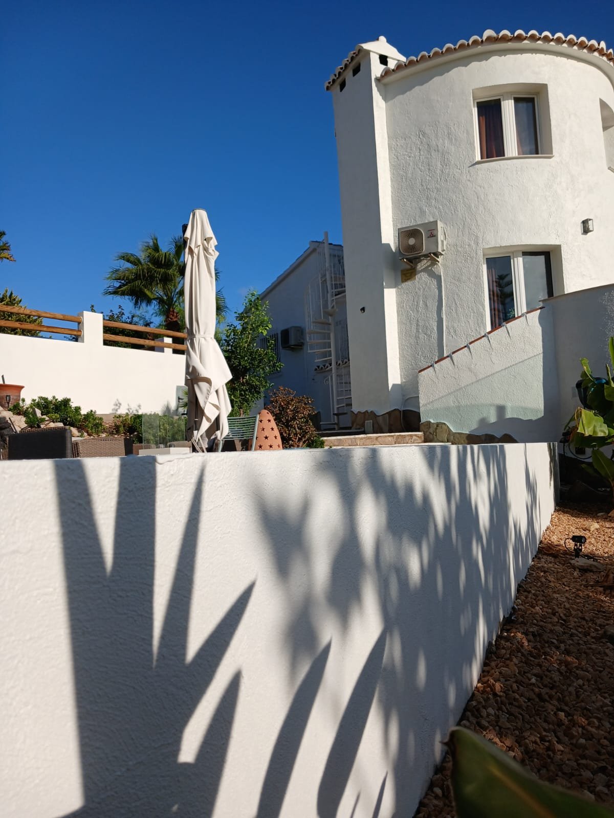 A white villa's round tower exterior, freshly painted, overlooking the garden