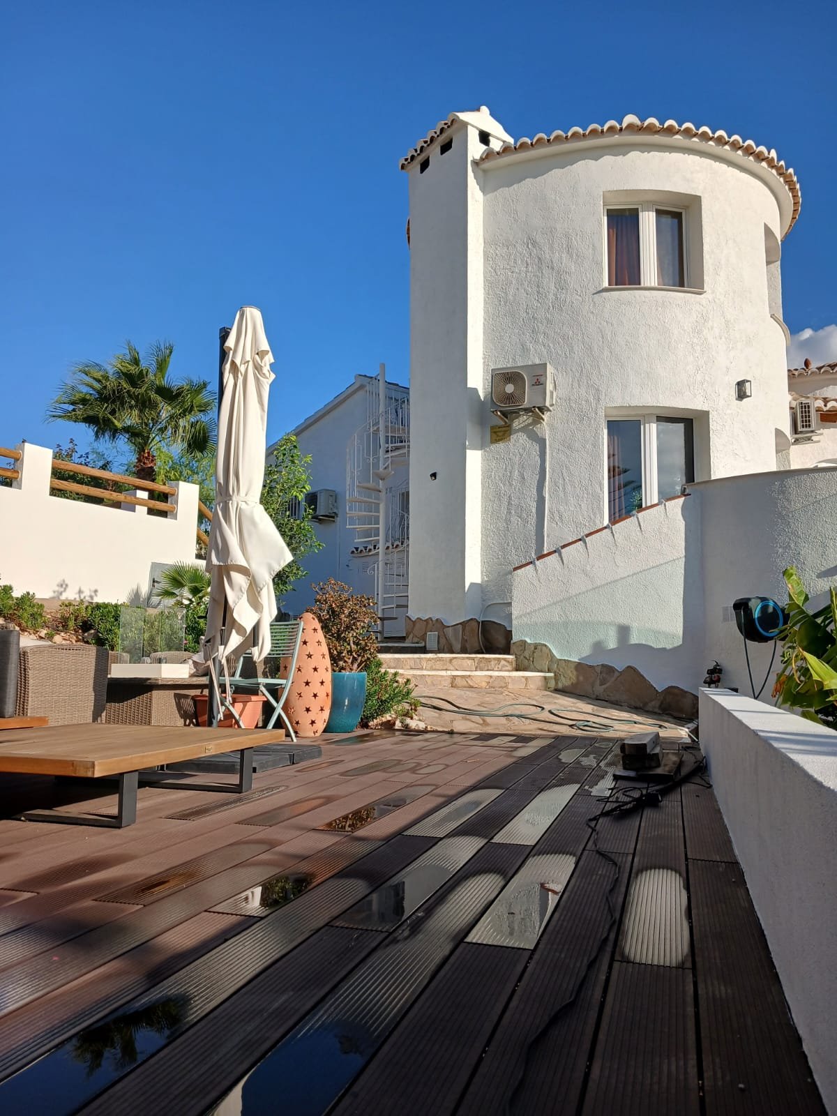 A round tower-shaped villa exterior, freshly painted white, overlooking a pool and palm trees